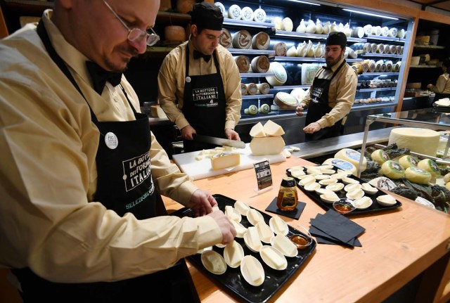 Vendors present different types of cheese at a stand during a press tour at FICO Eataly World agri-food park in Bologna on November 9, 2017. FICO Eataly World, said to be the world's biggest agri-food park, will open to the public on November 15, 2017. The free entry park, widely described as the Disney World of Italian food, is ten hectares big and will enshrine all the Italian food biodiversity. / AFP PHOTO / Vincenzo PINTO