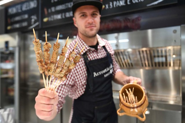 A vendor presents special Italian sheep 'kebab' at a stand during a press tour at FICO Eataly World agri-food park in Bologna on November 9, 2017. FICO Eataly World, said to be the world's biggest agri-food park, will open to the public on November 15, 2017. The free entry park, widely described as the Disney World of Italian food, is ten hectares big and will enshrine all the Italian food biodiversity. / AFP PHOTO / Vincenzo PINTO