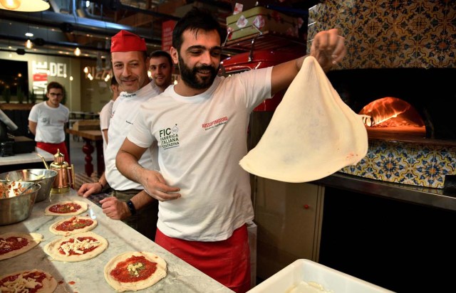 Pizza bakers prepare traditional pizza margherita during a press tour at FICO Eataly World agri-food park in Bologna on November 9, 2017. FICO Eataly World, said to be the world's biggest agri-food park, will open to the public on November 15, 2017. The free entry park, widely described as the Disney World of Italian food, is ten hectares big and will enshrine all the Italian food biodiversity. / AFP PHOTO / Vincenzo PINTO