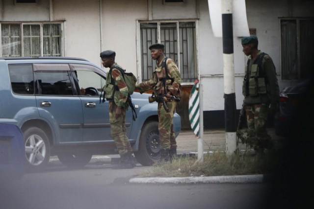 Zimbabwean soldiers control vehicles as they stand by an intersection as they regulate civilian traffic in Harare on November 15, 2017. Zimbabwe's military appeared to be in control of the country on November 15 as generals denied staging a coup but used state television to vow to target "criminals" close to President Mugabe. / AFP PHOTO / -