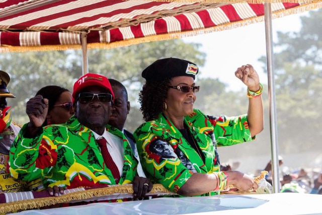 (FILES) This file photo taken on June 02, 2017 shows Zimbabwe President Robert Mugabe (L) with his wife Grace Mugabe (R) raising their fists in a vehicle before meeting delegates during a Zimbabwe ruling party Zimbabwe African National Union Ð Patriotic Front (ZANU-PF) youth rally at Rudhaka Stadium in Marondera. Zimbabwe's military appeared to be in control of the country on November 15, 2017 as generals denied staging a coup but used state television to vow to target "criminals" close to President Robert Mugabe. Mnangagwa's dismissal left Mugabe's wife Grace, 52, in prime position to succeed her husband as the next president -- a succession strongly opposed by senior ranks in the military. / AFP PHOTO / Jekesai NJIKIZANA