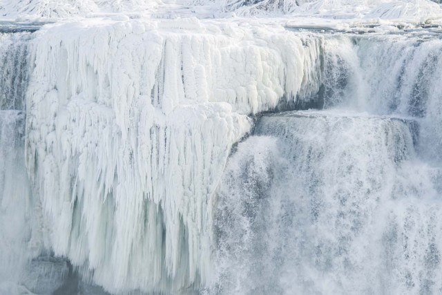 Ice hangs from the top of the American side of Niagara Falls on January 3, 2018. The cold snap which has gripped much of Canada and the United States has nearly frozen over the American side of the falls. / AFP PHOTO / Geoff Robins