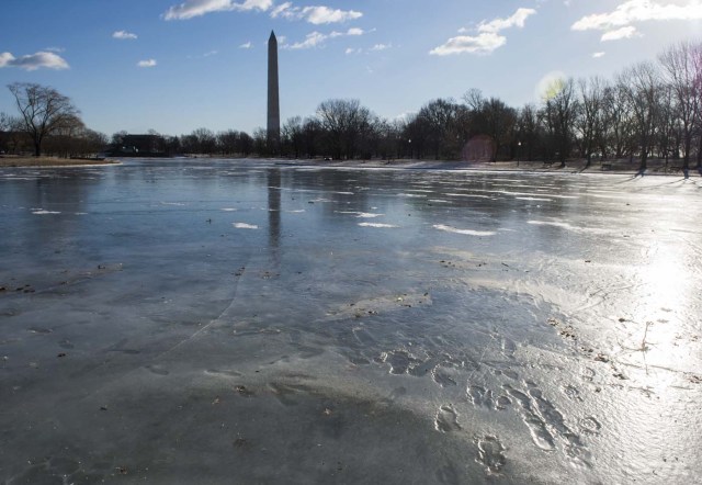 Footprints are seen frozen in the Constitution Garden pond near the Washington monument in Washington, DC on January 5, 2018. The National Weather Service said that very cold temperatures and wind chills will follow for much of the eastern third of the US through the weekend. A cold wave gripping a large section of the United States had already been blamed for a dozen deaths. / AFP PHOTO / Andrew CABALLERO-REYNOLDS
