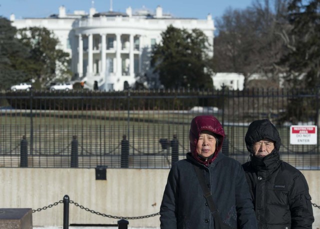 Tourists have photos taken near the White House in Washington, DC on January 5, 2018. The National Weather Service said that very cold temperatures and wind chills will follow for much of the eastern third of the US through the weekend. A cold wave gripping a large section of the United States had already been blamed for a dozen deaths. / AFP PHOTO / ANDREW CABALLERO-REYNOLDS