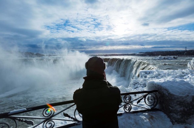 A visitor takes pictures near the brink of the ice covered Horseshoe Falls in Niagara Falls, Ontario, Canada, January 3, 2018. REUTERS/Aaron Lynett