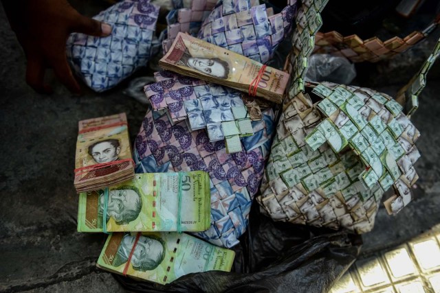 Wilmer Rojas, 25, shows the purses he sewn up, using Bolivar bills in Caracas, on January 30, 2018. A young Venezuelan tries to make a living out of devalued Bolivar banknotes by making crafts with them. / AFP PHOTO / FEDERICO PARRA