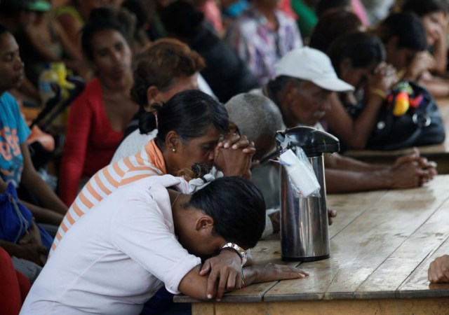 Venezuelans pray as they gather at a dining facility organised by Caritas and the Catholic church, in Cucuta, Colombia February 21, 2018. Picture taken February 21, 2018. REUTERS/Carlos Eduardo Ramirez