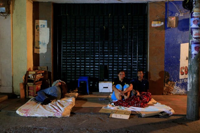 People sit on a makeshift bed, on a street, where Venezuelan migrants gather to spend the night, in Maicao, Colombia February 15, 2018. Picture taken February 15, 2018. REUTERS/Jaime Saldarriaga