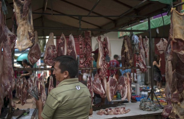 A Venezuelan immigrant buys meat in a butcher shop in a street fair in the city of Boa Vista, Roraima, Brazil, on February 25, 2018. When the Venezuelan migratory flow exploded in 2017 the city of Boa Vista, the capital of the state of Roraima, 200 kilometers from the Venezuelan border, began to set up shelters as people started to settle in squares, parks and corners of this city of 330,000 inhabitants of which 10 percent is now Venezuelan. / AFP PHOTO / Mauro PIMENTEL