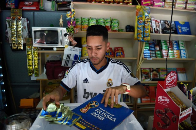 A newsstand vendor shows the collectible trading card album Russia 2018 in Caracas on April 2, 2018. Due to the economic crisis in Venezuela, fans are not able to collect the FIFA World Cup Russia 2018 picture cards. / AFP PHOTO / FEDERICO PARRA / TO GO WITH AFP STORY BY ALEXANDER MARTINEZ