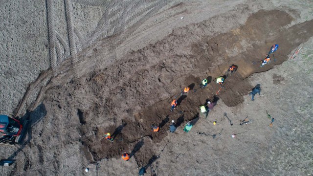 This aerial picture taken with a drone on April 13, 2018 shows archaeologists looking for a treasure in Schaprode, northern Germany. A 13-year-old boy and a hobby archaeologist have unearthed a "significant" trove in Germany which may have belonged to the legendary Danish king Harald Bluetooth who brought Christianity to Denmark. A dig covering 400 square metres (4,300 square feet) that finally started over the weekend by the regional archaeology service has since uncovered a trove believed linked to the Danish king who reigned from around 958 to 986. Braided necklaces, pearls, brooches, a Thor's hammer, rings and up to 600 chipped coins were found, including more than 100 that date back to Bluetooth's era. / AFP PHOTO / dpa / Stefan Sauer / Germany OUT