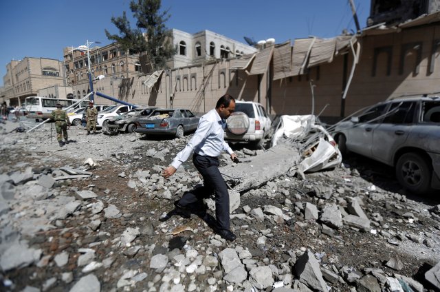 Un hombre pasa frente a automóviles dañados fuera del complejo presidencial después de que fue alcanzado por ataques aéreos en Sanaa, Yemen, el 7 de mayo de 2018. REUTERS / Khaled Abdullah
