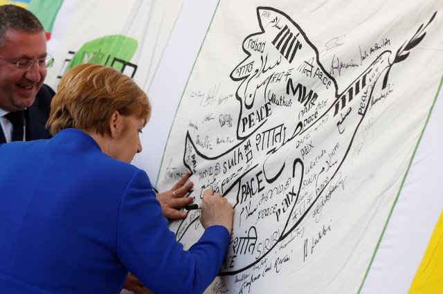 La canciller alemana, Angela Merkel, firma una bandera de la paz durante su visita a Asís, Italia, el 12 de mayo de 2018. REUTERS / Yara Nardi 