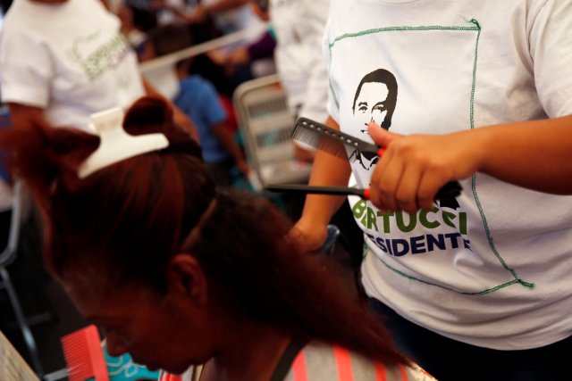 Una mujer se corta el pelo por un voluntario del candidato presidencial venezolano Javier Bertucci de la fiesta "Esperanza por el Cambio", durante un mitin de campaña en Caracas, Venezuela el 12 de mayo de 2018. REUTERS / Carlos Jasso