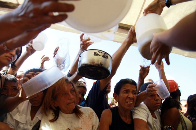 La gente espera la sopa gratis entregada por los voluntarios del candidato presidencial venezolano Javier Bertucci del partido "Esperanza por el Cambio", durante un mitin de campaña en Caracas, Venezuela el 12 de mayo de 2018. REUTERS / Adriana Loureiro