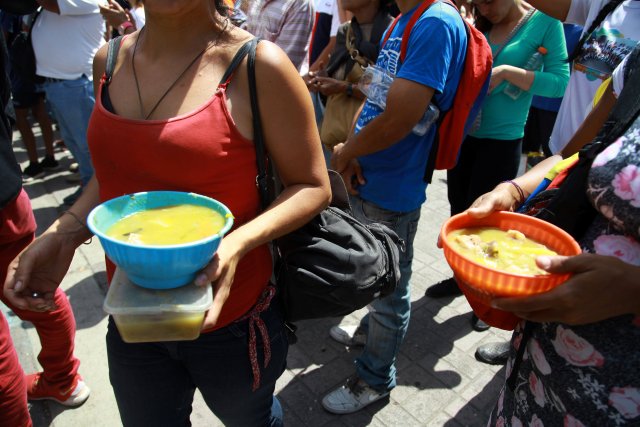 Los asistentes sostienen platos de sopa repartidos por voluntarios del candidato presidencial venezolano Javier Bertucci del partido "Esperanza por el Cambio", durante una manifestación de campaña en Caracas, Venezuela el 12 de mayo de 2018. REUTERS / Adriana Loureiro