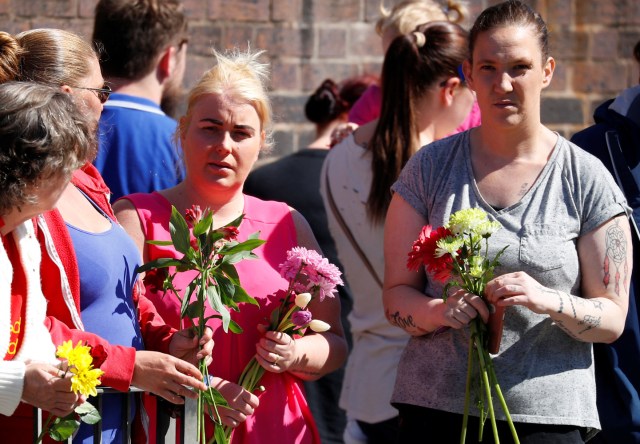 Las personas que llevan tributos florales esperan que el cortejo fúnebre del niño Alfie Evans pase Goodison Park, el estadio del club de fútbol Everton, en Liverpool, Reino Unido, el 14 de mayo de 2018. REUTERS / Phil Noble